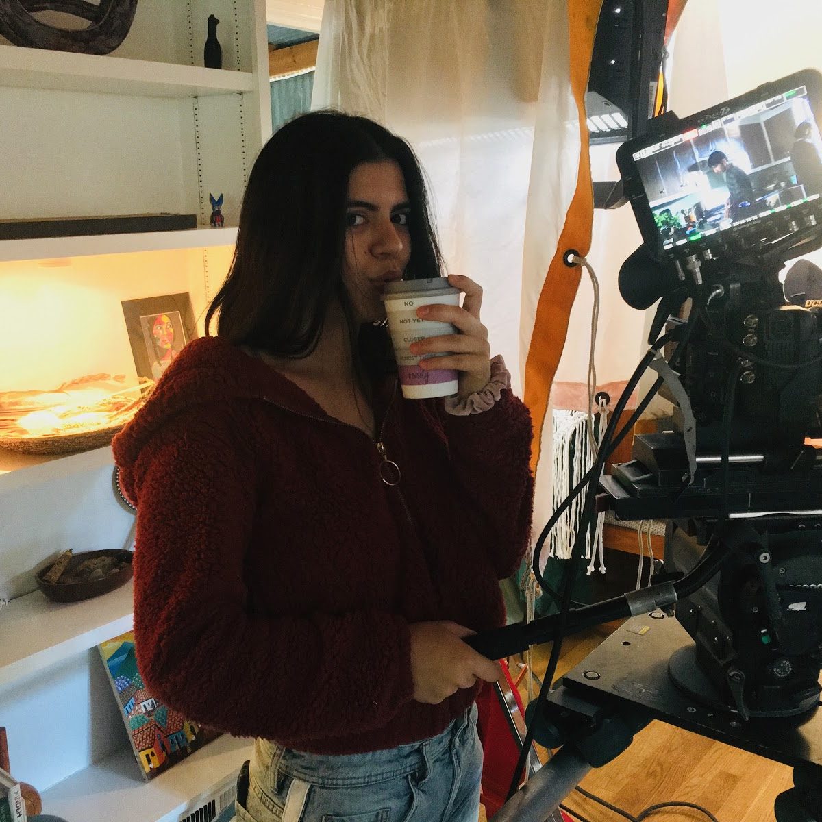 Almarosa drinking coffee while operating a film camera